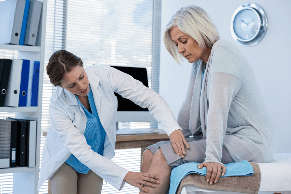 El médico examina a un paciente con artrosis de la articulación de la rodilla. 